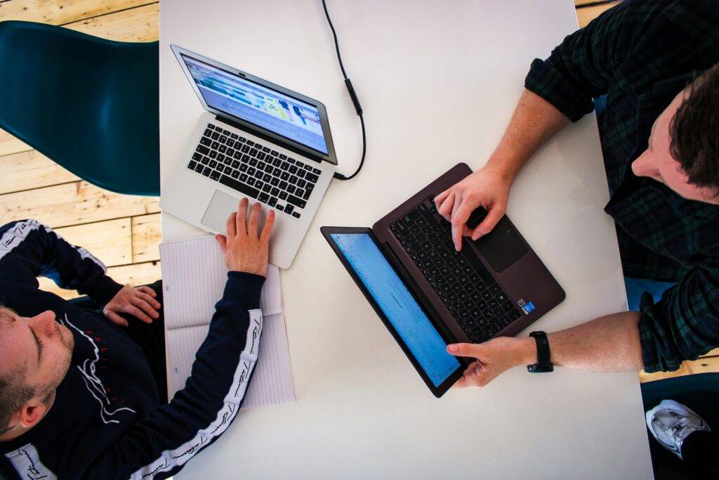 Two people working on laptops at a table