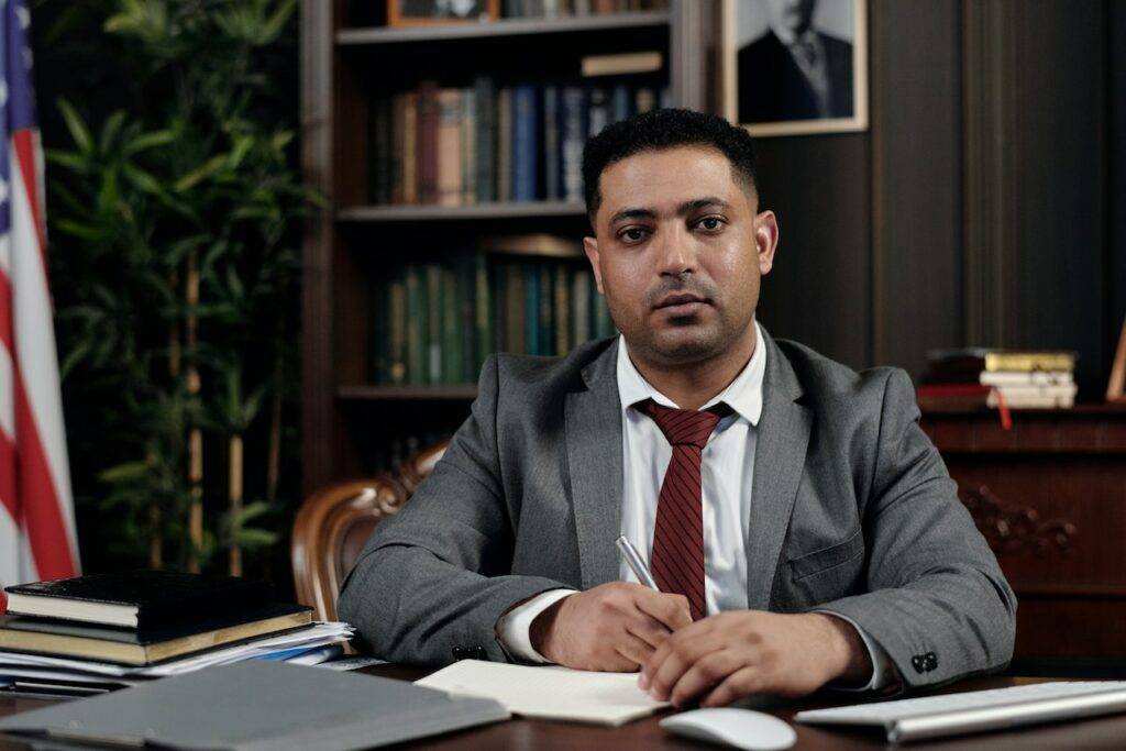 Man in suit sitting down with a pen