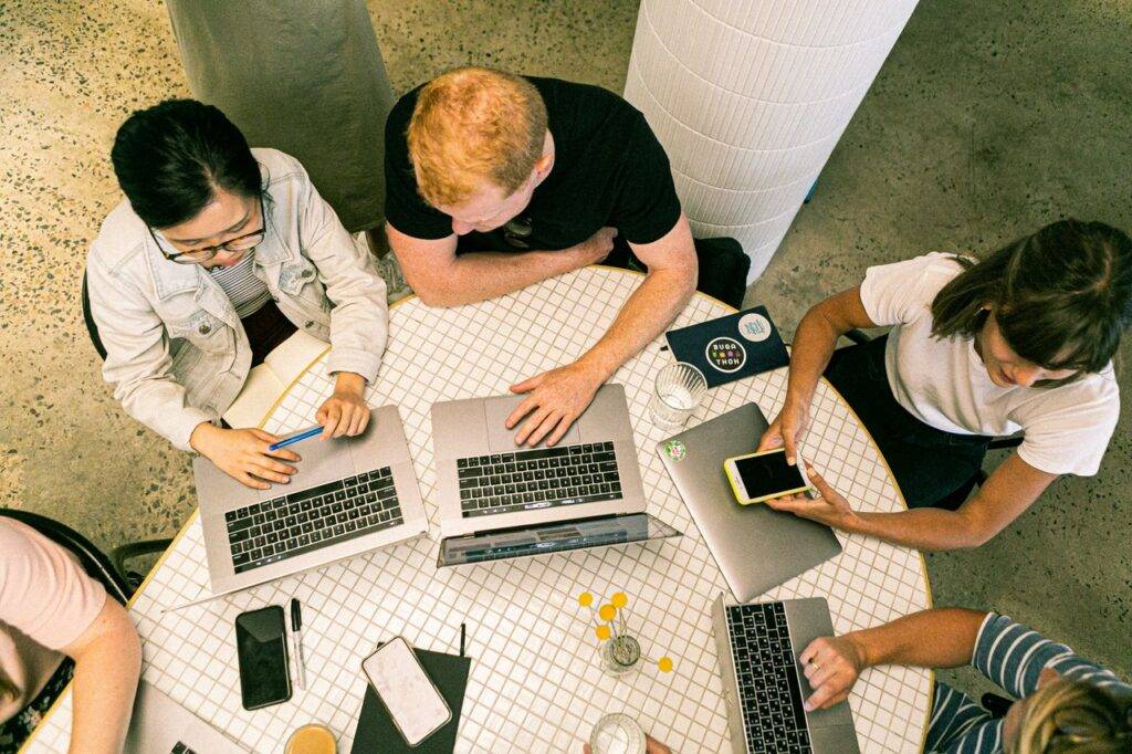 Group of people working with laptops and phones on a table