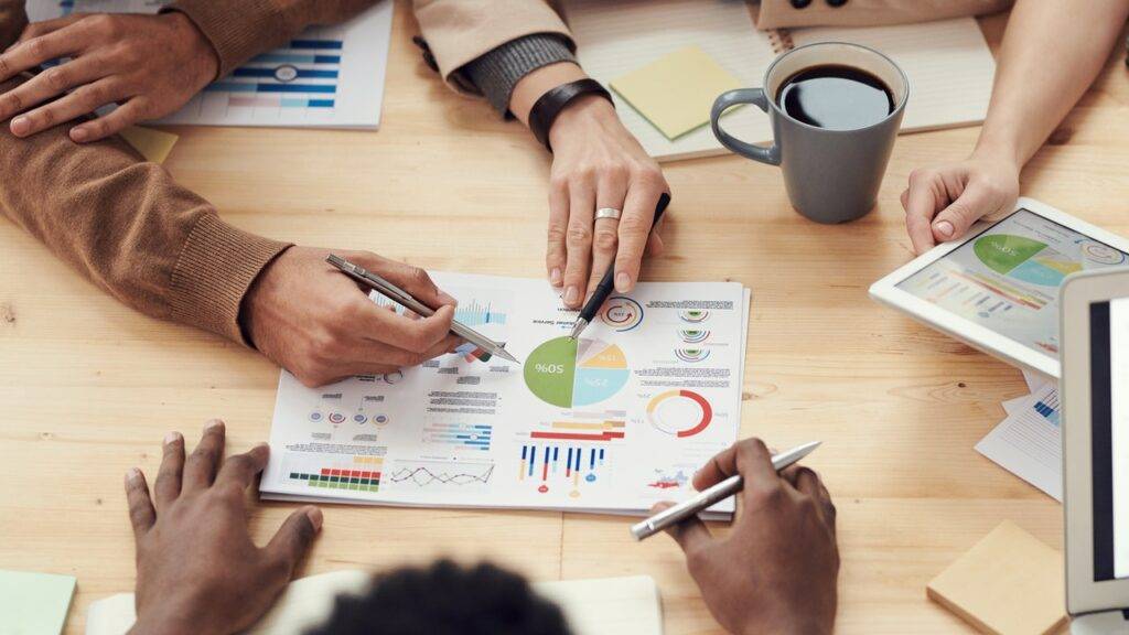 A group of people pointing at a graph on paper with pens