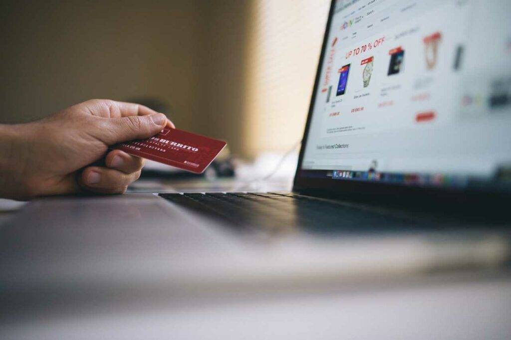 Hand with a card and a shopping website on a computer