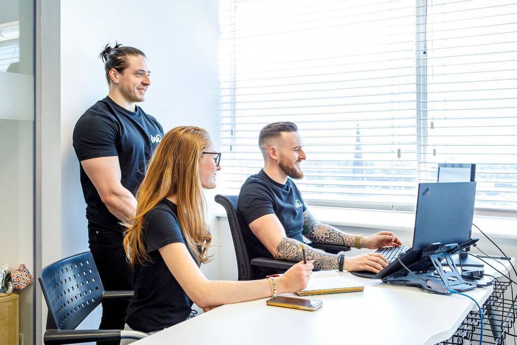 Three Ink Digital members smiling while working together