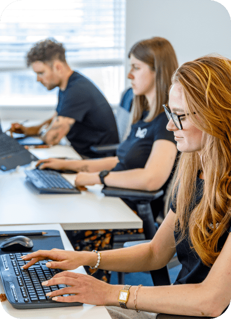 Three people at a desk working on computers